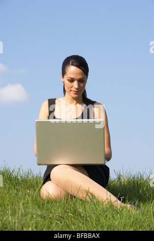 Woman Using Laptop Outdoors In Summer Countryside Stock Photo