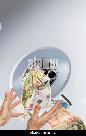 money going down the plughole into sink drain conceptual image Stock Photo
