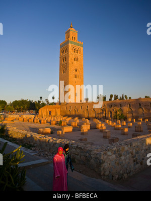 MARRAKESH, MOROCCO - Two women walk by Koutoubia Mosque, and its moorish minaret, built in 12th century. Stock Photo