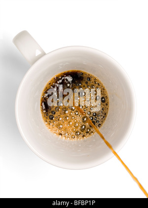 Fresh coffee being poured into a coffee cup on a white background. Stock Photo