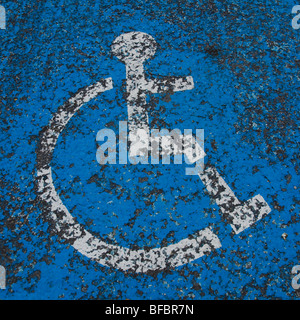 Wheelchair symbol dor disabled parking space painted on tar road surface. Stock Photo