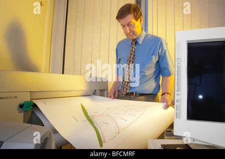 draughtsman with printer plotter of plan and computer monitor in office Stock Photo
