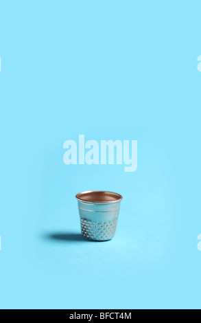 thimble sits upright on blue simple background Stock Photo