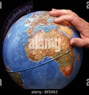 Close up male hand on world globe concept image getting a grip on wider view of worldwide affairs such as in the African Continent a studio shot in UK Stock Photo