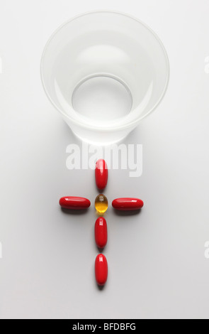 pills forming a cross next to a glass of water