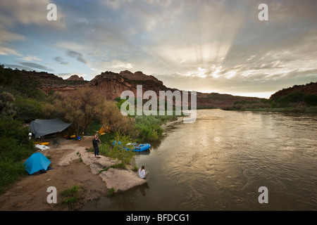 A group of people camp after rafting on the Colorado River at sunset. Stock Photo