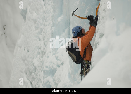 A young man ice climbing a frozen waterfall with a backpack in Colorado. Stock Photo