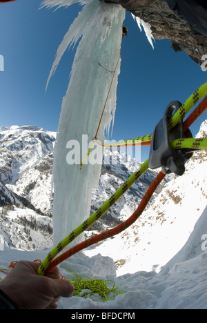 View of climbing rope used by a professional male ice climber as he ascends a frozen waterfall pillar.