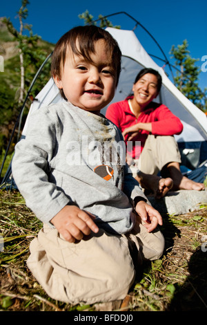 Mother watches 14 month old son play in meadow at camp. Backpacking trip Maroon Bells in Snowmass Wilderness outside Aspen Stock Photo