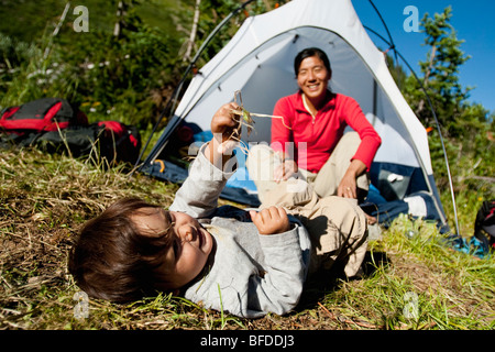 Mother watches 14 month old son play in meadow at camp. Backpacking trip Maroon Bells in Snowmass Wilderness outside Aspen Stock Photo