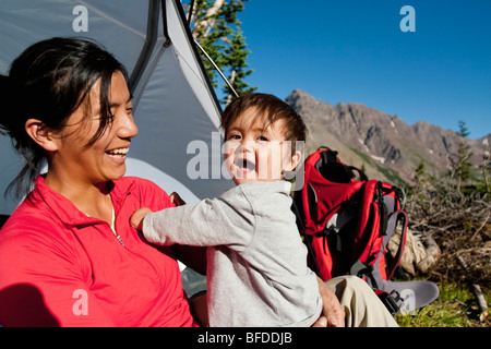 Mother watches 14 month old son play in meadow at camp. Backpacking trip Maroon Bells in Snowmass Wilderness outside Aspen Stock Photo