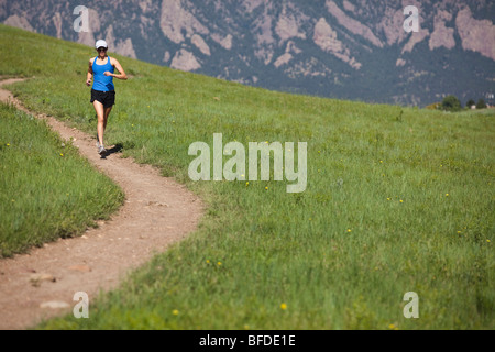 A woman runs on the curving Mesa Trail with the foothills in the background near Boulder, Colorado. Stock Photo