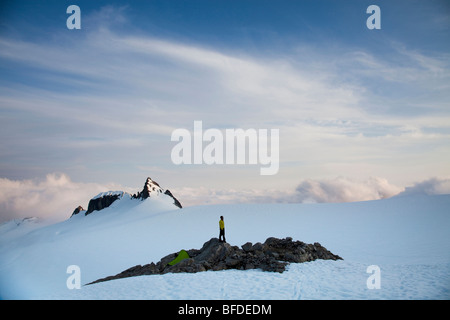 A climber stands on a rock outcrop in the middle of a glacier while climbing in the North Cascades, WA.