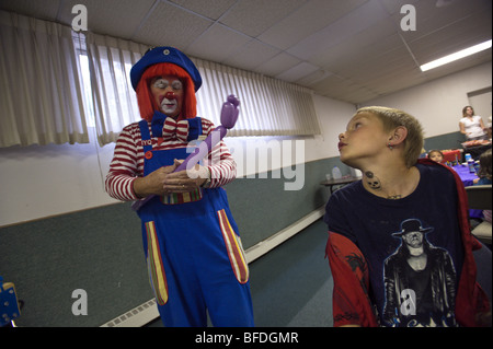 A clown talks to a ten year old boy  who is off and on homeless or living in motels at a party and dinner put on for families an Stock Photo