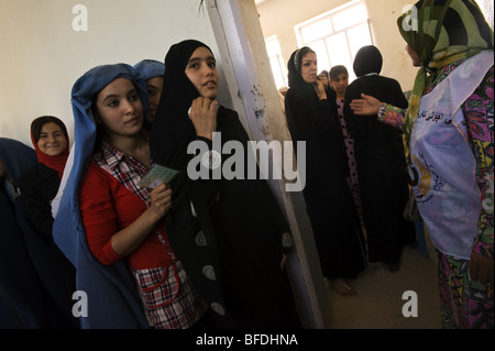 Women hold their registration cards as they wait in line to vote in the Sultan Razia Girls High school on the day of presidentia Stock Photo