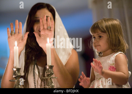 Mother and daughter blessing on Shabbat candles. Stock Photo