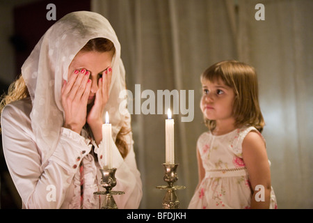 Mother and daughter blessing on Shabbat candles. Stock Photo