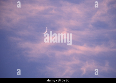 Crescent Moon Behind Cirrus Cloud in Evening Stock Photo