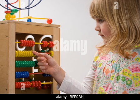 Child/girl playing with an abacus sliding the beads across with her fingers Stock Photo