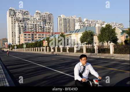 A man riding a bicycle past a compound of luxurious apartments and villas in Songjiang on the outskirts of Shanghai. 2009 Stock Photo