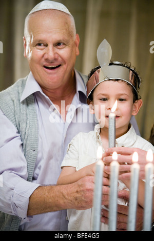 Grandfather and grandson lighting Hanukkah candles. Stock Photo