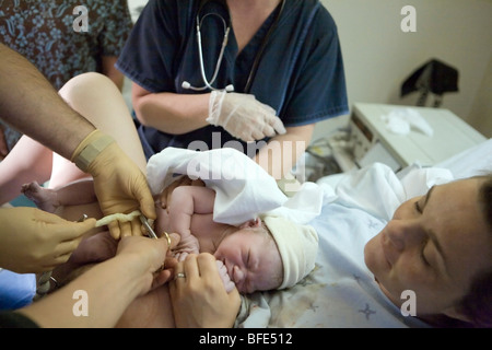 36 year old woman with her newborn as umbilical cord is cut, Chateauguay, Quebec, Canada Stock Photo