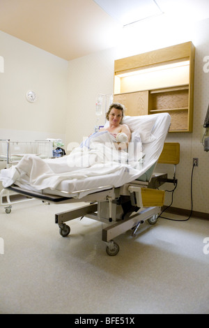 36 year old woman lying in hospital bed with newborn in her arms, Chateauguay, Quebec, Canada Stock Photo