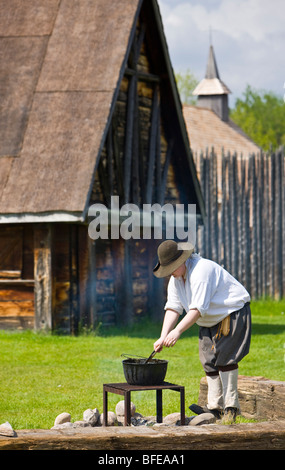 Costumed character tending a pot over a fire in Sainte-Marie Among Hurons settlement in town of Midland Ontario Canada Stock Photo