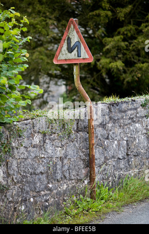 Double bend first to the left road sign. Crooked sign on crooked post. Pen-y-Dyffryn. Wales. United Kingdom. Stock Photo