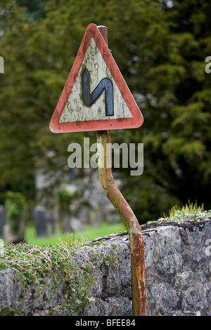 Double bend first to the left road sign. Crooked sign on crooked post. Pen-y-Dyffryn. Wales. United Kingdom. Stock Photo
