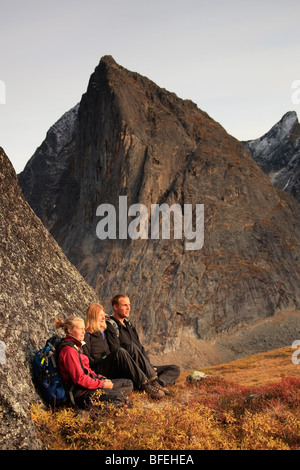 Hikers taking a break on rock while climbing in Tombstone Territorial Park, Yukon, Canada Stock Photo