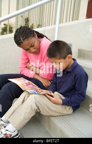 young person people Multi ethnic ethnically diverse teenage girl reads book Hispanic boy steps mentor mentoring mentors child helping another  MR  © Myrleen Pearson Stock Photo