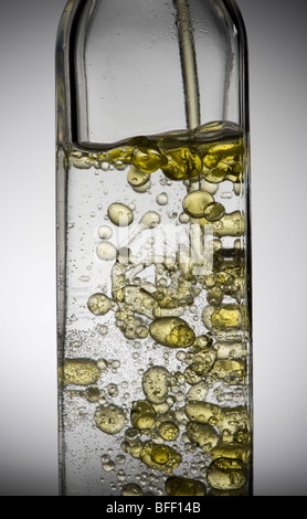 Olive oil droplets in bottle of water Stock Photo