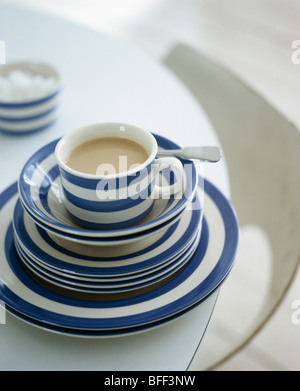 Close-up of blue+white striped Cornish-ware cup on stack of matching bowls and plates