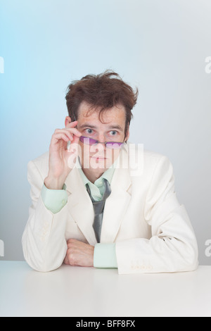 The tousled young man in eyeglasses sitting at a table Stock Photo