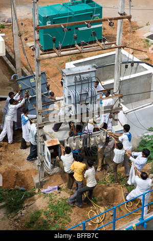 Indian men changing an electricity transformer without machinery. Puttaparthi, Andhra Pradesh, India Stock Photo