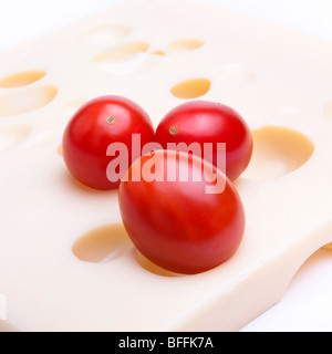 Close up of cherry plum tomatoes against background of swiss cheese. Stock Photo