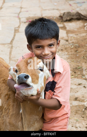 Young indian boy hugging a calf in a rural indian village. Andhra Pradesh, India Stock Photo