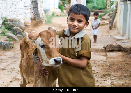 Young indian boy hugging a calf in a rural indian village. Andhra Pradesh, India Stock Photo