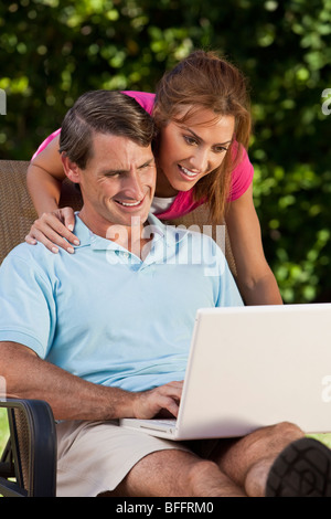 Portrait shot of an attractive, successful and happy middle aged man and woman couple in their thirties using a laptop computer Stock Photo