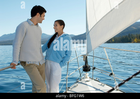 Young couple standing on bow of sailboat Stock Photo