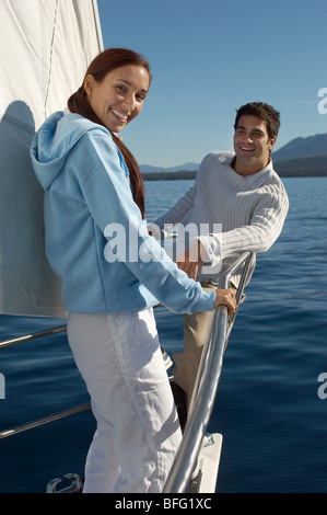 Young couple standing on bow of sailboat, (portrait) Stock Photo