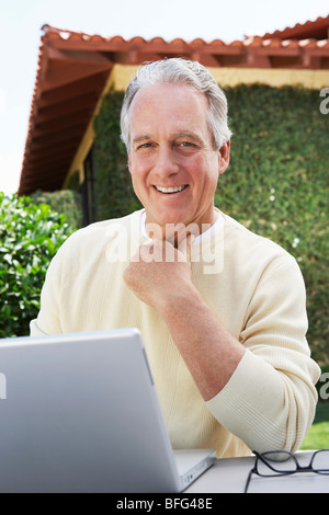 Middle aged Man Using Laptop in Garden Stock Photo