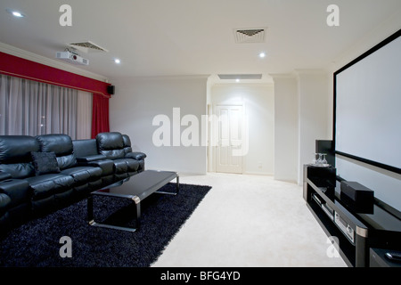 home theater room with black leather recliner chairs projector screen on wall and projector in ceiling. Stock Photo