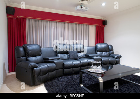 home theater room with black leather recliner chairs, red curtains, black rug and table with wine glasses Stock Photo