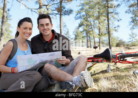 Young couple sitting outdoors reading map, portrait. Stock Photo