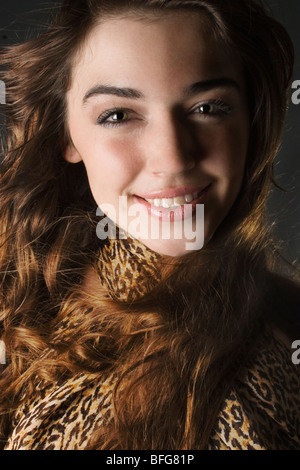 A beautiful young brunette woman smiling and wearing a leopard print scarf. Stock Photo