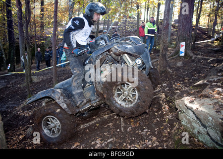 Man rides all-terrain vehicle (ATV) on steep uphill terrain in woods. Trial off-road biking. Sweden. Stock Photo