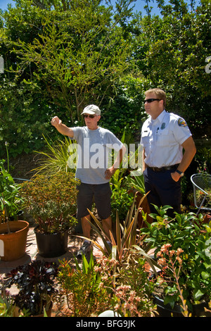 A county fire department inspector discusses the fire hazards of landscape plantings with a Southern California homeowner Stock Photo