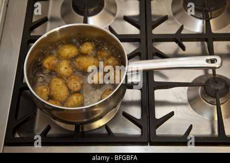 Pan of potato's boiling on a gas stove hob. Stock Photo